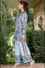 Woman wearing a patterned outfit standing outdoors with greenery in the background
