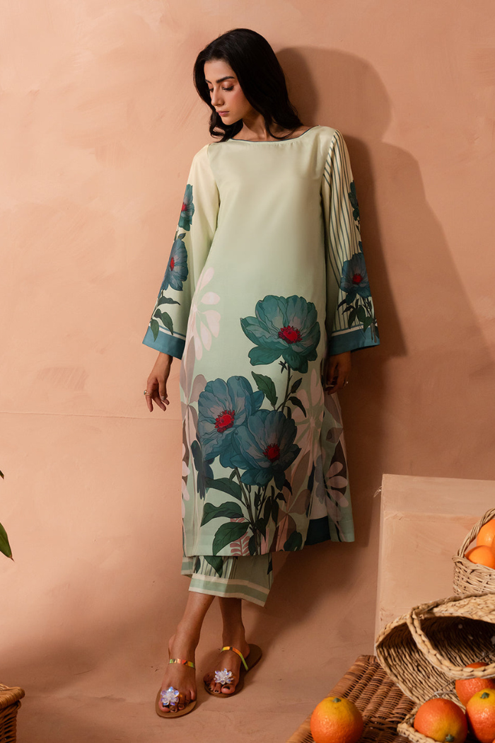 Woman wearing a floral dress against a beige wall with fruits on the floor.