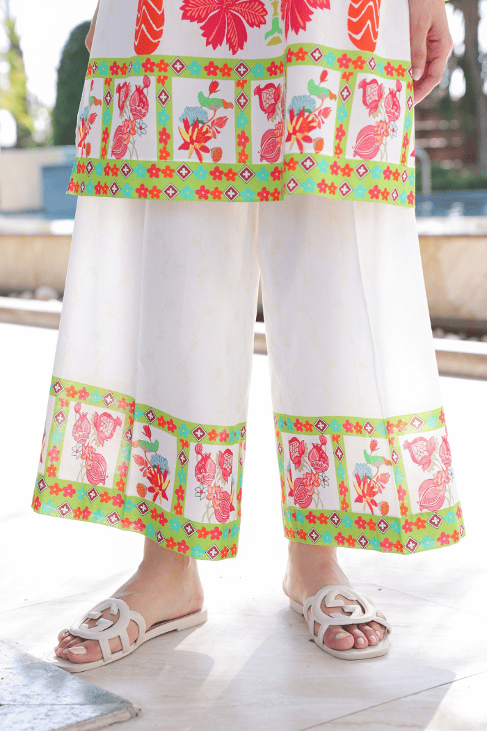 Person wearing a colorful floral dress with a patterned trim on a blurred outdoor background