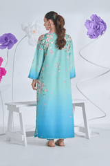 Woman wearing a light blue floral dress standing in front of decorative flowers on a white background
