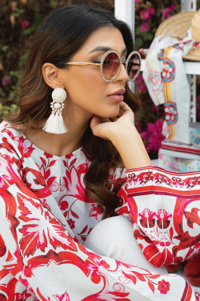 Woman wearing a red and white patterned outfit with sunglasses and tassel earrings.