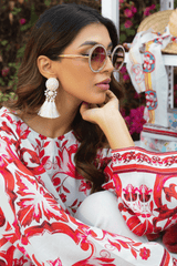 Woman wearing a red and white patterned outfit with sunglasses and tassel earrings.