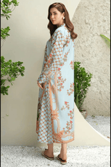 Woman wearing a light blue floral dress with a patterned shawl, standing against a neutral background.