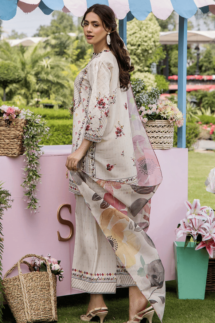 Woman in a floral outfit standing in a garden setting with decorative elements.