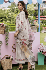 Woman in a floral outfit standing in a garden setting with decorative elements.