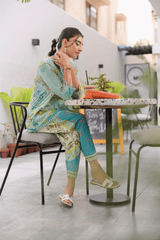 Woman in a colorful outfit sitting at a table with food in an outdoor setting