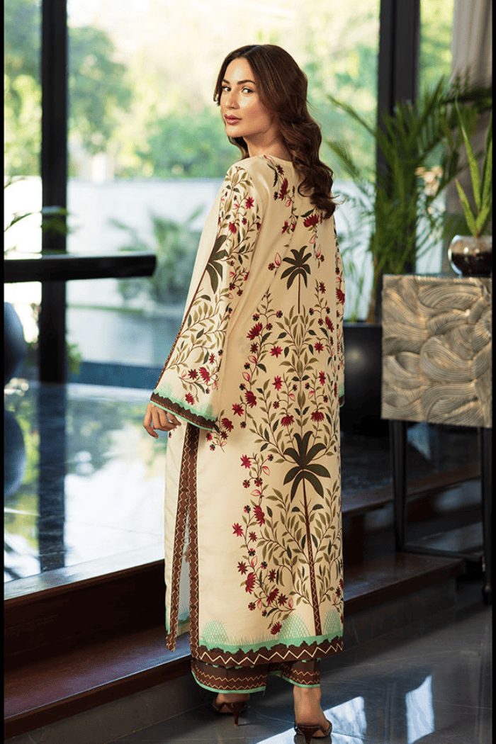 Woman wearing a cream-colored embroidered outfit standing indoors with plants in the background