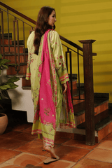 Woman in a green and pink traditional outfit standing on a staircase with a yellow wall background.