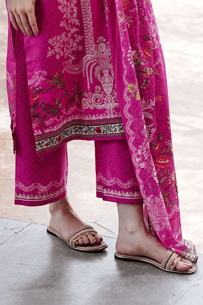 Person wearing a bright pink traditional outfit with intricate white on a light background