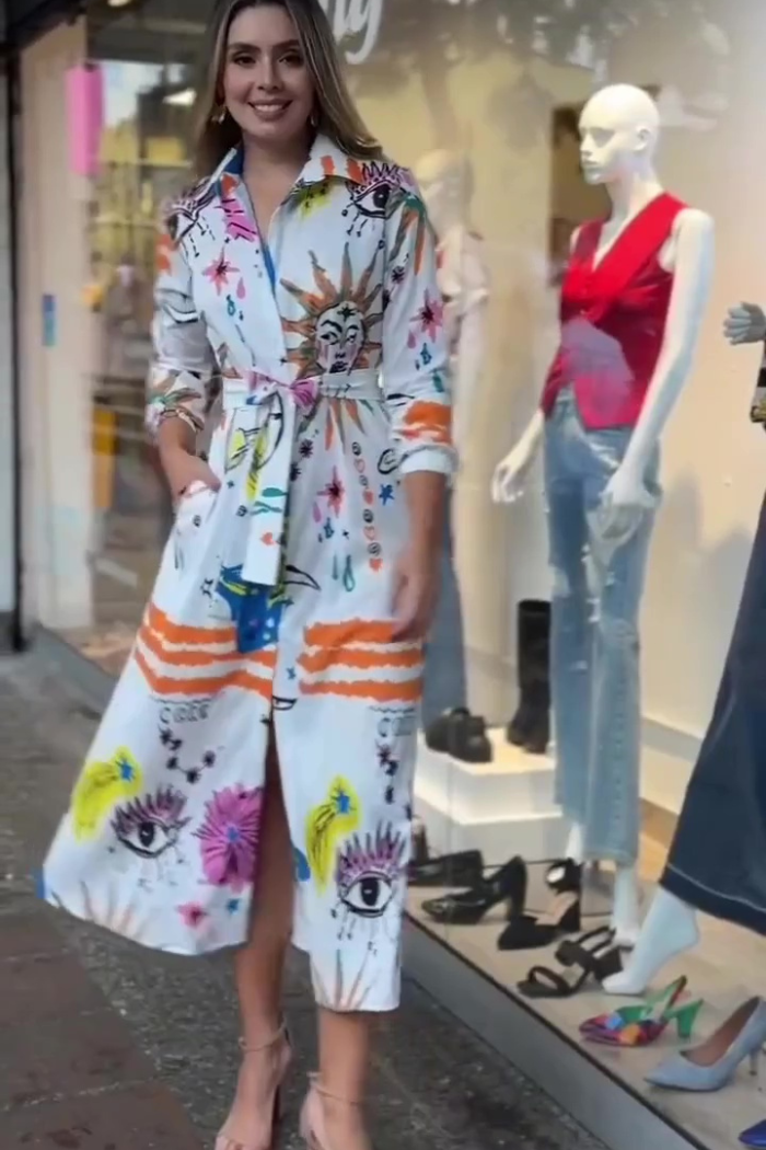 Woman wearing a colorful outfit standing in front of a store window with mannequins.