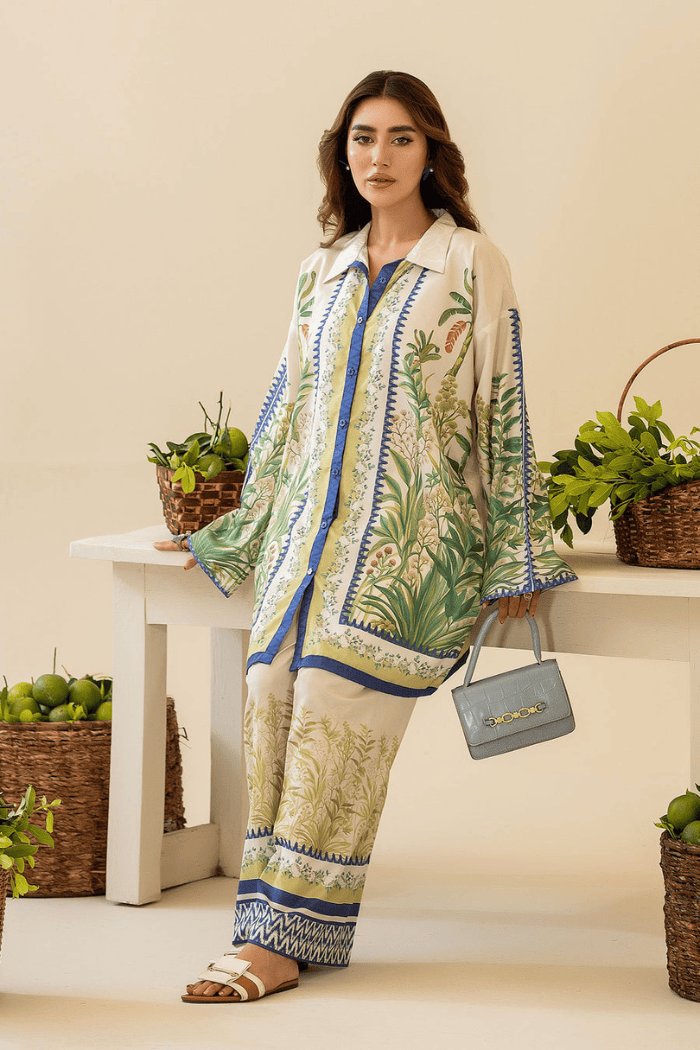 Woman in a patterned outfit standing in a room with plants and a table.