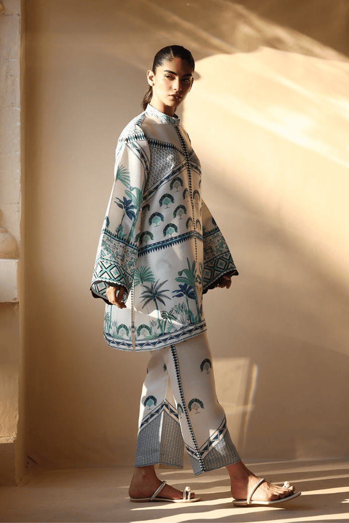 Woman wearing a patterned outfit standing in a softly lit room.