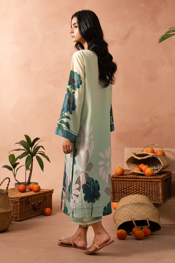 Woman wearing a light green floral dress standing in a room with wicker baskets and oranges.