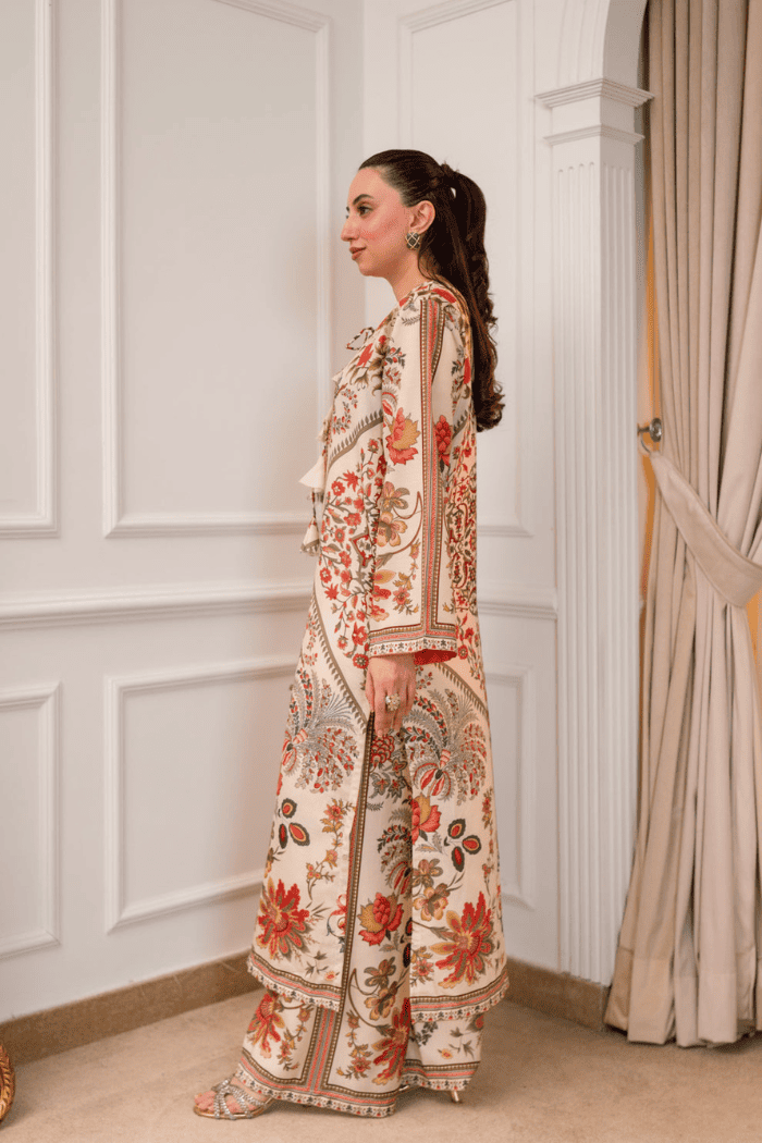 Woman wearing a floral outfit standing in a room with white walls and a beige curtain.