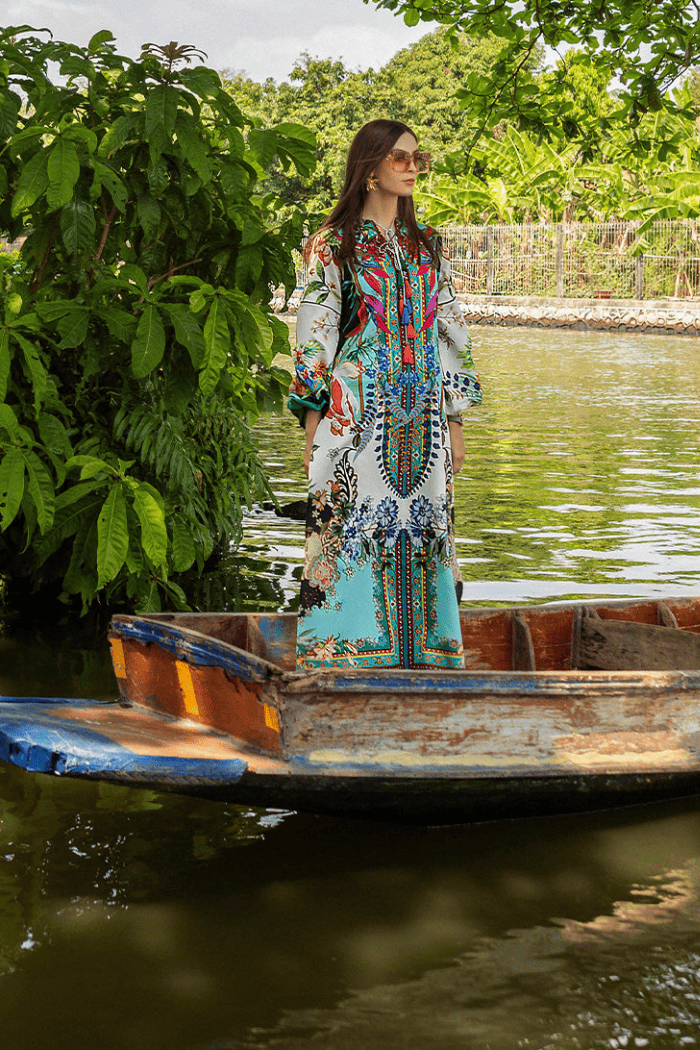 Woman in a colorful dress standing on a boat by a river with greenery around