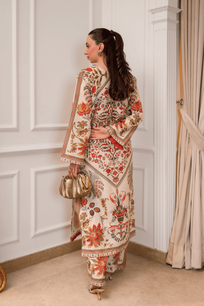 Woman in a floral dress standing against a white paneled wall.