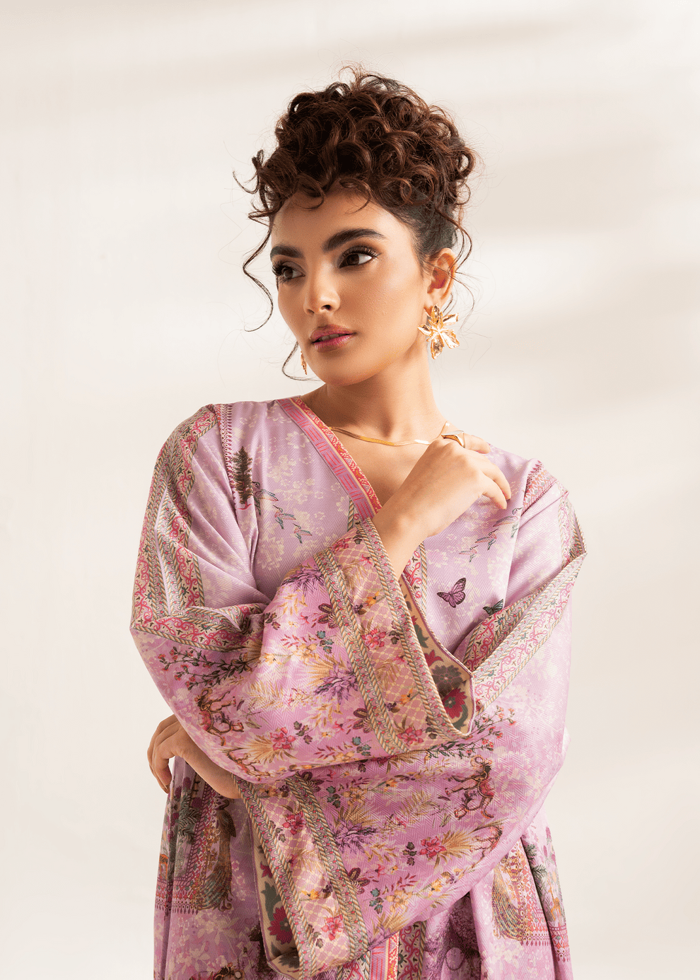 Woman wearing a pink floral kimono-style garment against a plain background