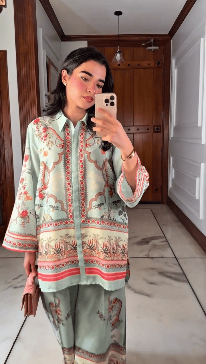 Person wearing a patterned outfit taking a mirror selfie in a home setting.